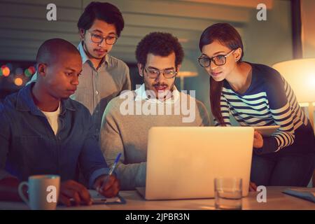 Putting their heads together to complete the project. a group of designers working late in an office. Stock Photo