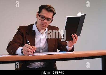 Man working at his desk. Business executive dressed in a suit wearing glasses and holding a black notepad. Business man working while signing papers. High quality photo Stock Photo