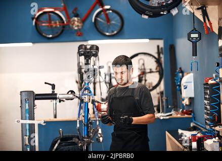 Doing what he does best, bicycle repair. a man working in a bicycle repair shop. Stock Photo