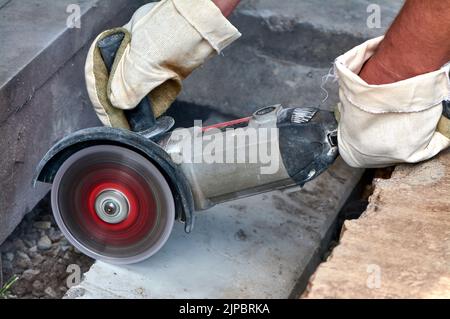 A worker with a circular saw cuts a concrete block in close-up. Stock Photo
