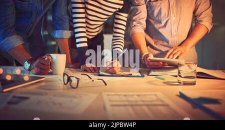 Getting hands on for the late shift. a group of unrecognizable designers working late in an office. Stock Photo