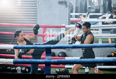 Fit, active and healthy kickboxing athletes exercise training together in boxing ring in modern sports gym. Sporty and strong woman workout with her Stock Photo