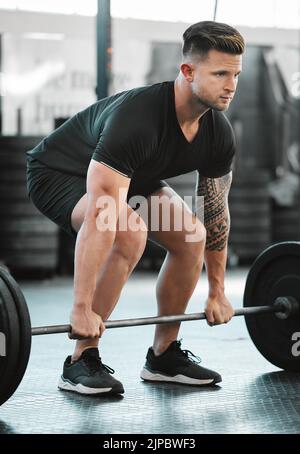 Fit, active and strong man with barbell weight for lifting in gym workout, exercise and training. Serious, motivated and sporty athlete building Stock Photo