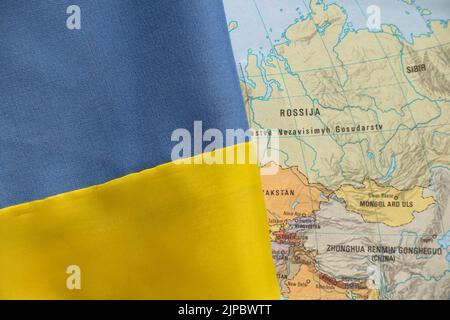 The yellow-blue national flag of Ukraine and next to it lies a map of Russia, stop the war in Ukraine, Ukraine and Russia, Russia's aggression against Stock Photo