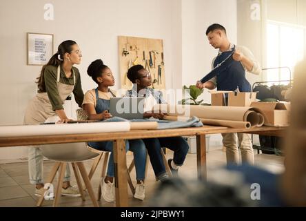 Serious, young and creative clothing designers planning with laptop, working on clothes and learning about material at a studio together. Diverse Stock Photo