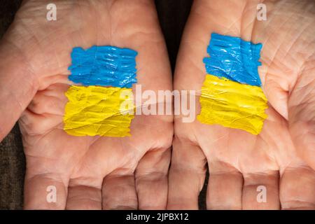 The yellow-blue flag of Ukraine is painted on the hands of the old woman, Stop the war and patriotism, peace in Ukraine, stop the war in Ukraine. Peac Stock Photo