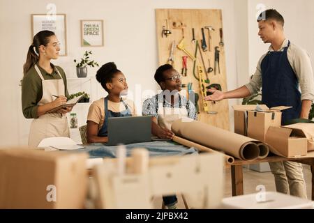 Creative leader, manager or boss talking to his design team in a modern studio or workshop. Male designer speaking to a group of colleagues and Stock Photo