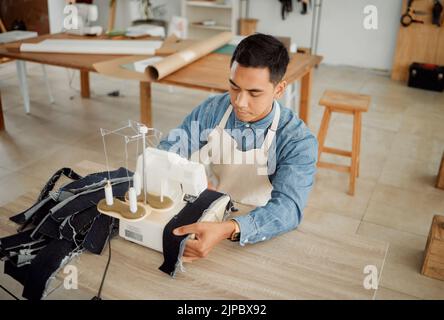 Creative fashion designer or seamstress tailor working on sewing trendy and stylish clothing garment in design studio workshop. Young male dressmaker Stock Photo