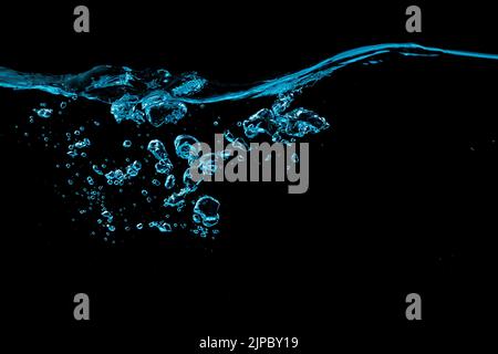 Clear water surface with ripple and bubbles in blue light on a black nature background Stock Photo