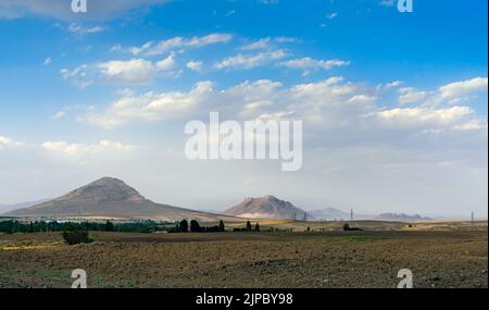 A view of a village on the side of a mountain with a cloudy sky Stock Photo