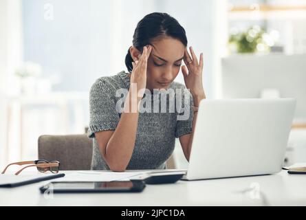 Headache, tired and stressed young businesswoman with financial problems on laptop sitting at desk. Professional female accountant in accounting Stock Photo