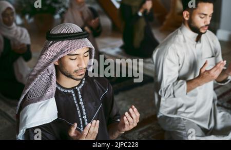 Religion, Arabic and Muslim family praying, kneeling and worshipping together in an Islamic Mosque to honor and God. A religious, traditional and Stock Photo