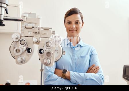 Confident, happy and proud optometrist standing with arms crossed, ready for checkup and preparing equipment in an optometry office. Smiling Stock Photo