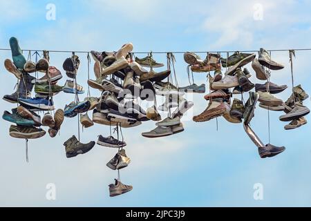 Old shoes hanging on a rope across the shopping street Norderstrasse in the city of Flensburg, Germany, landmark and tourist attraction with unclear o Stock Photo
