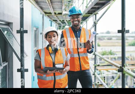 Builder and engineer working together as a construction team on a building site and standing on scaffolding. Portrait of a man and woman in a hardhat Stock Photo