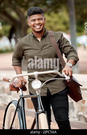 Happy business man riding a bicycle, commuting and staying active while traveling in city. Portrait of a smiling, cheerful and positive guy cycling on Stock Photo