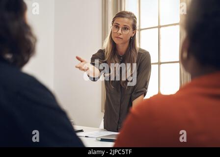Young, upset and professional businesswoman in a meeting with two workers having an argument. Group, team or people training and discussing at the Stock Photo