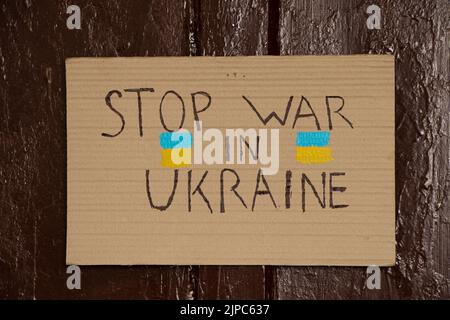 Paper signs with slogans stop the war in Ukraine hang on the brown door of the house, the war in Ukraine 2022 Stock Photo