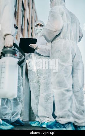 Healthcare workers outside in protective gear during an outbreak in the city. A group of scientists wearing hazmat suits, cleaning urban areas. Safety Stock Photo