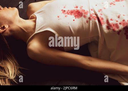 A murdered and tortured Ukrainian woman in a white dress and bloodstains lies on the floor of the house, a protest action of Ukrainian women Stock Photo