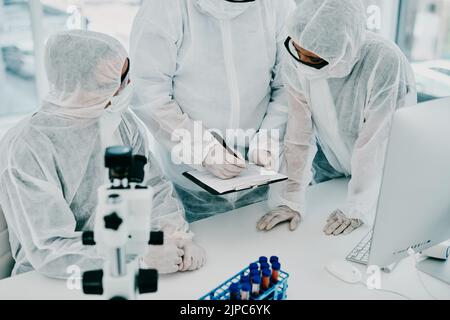 Team of scientists, pathologists and doctors in hazmat suits discussing forensic research and plans in a lab. Medical experts working on tests Stock Photo