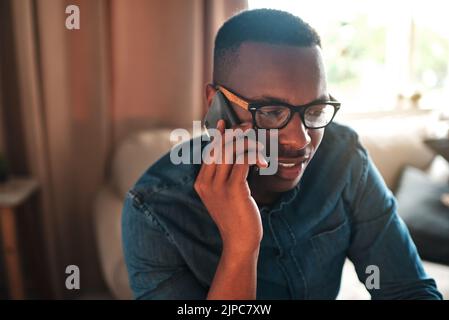 Young student talking on a phone call to a friend, colleague or family member. Black male university or college learner studying design, marketing or Stock Photo