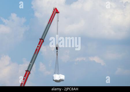 Several transport bags hang on the hook of a crane Stock Photo