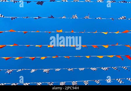 Many lines rows of isolated flag pennats chains garlands racing symbol against clear blue cloudless summer sky - Zandvoort, Netherlands Stock Photo