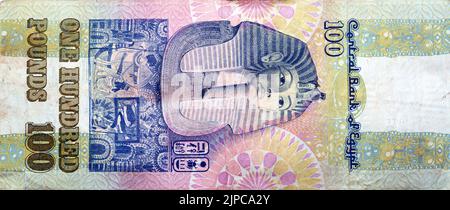 Large fragment of reverse side of an old 100 LE EGP one hundred Egyptian cash money banknote Tutankhamen's mask above frieze at centre of vertical for Stock Photo