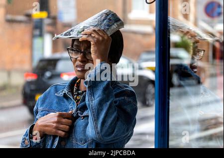 Makeshift rain cover   Wet weather finally in London after rough conditions  heavy showers caught out some others had come prepared with umbrellas aro Stock Photo