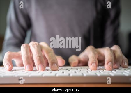 A man typing on a low profile computer keyboard Stock Photo