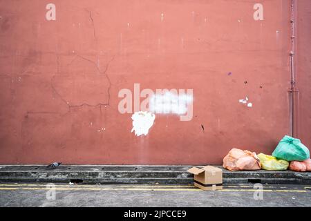 Old red wall with garbage bag Stock Photo