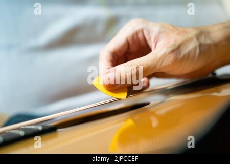 Guitarist playing acoustic guitar with a guitar pick Stock Photo