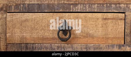 Old-fashioned wooden drawer bronze handle -part of an old wordrobe Stock Photo