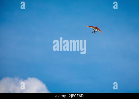 A view of hang glider flying high in the blue sky Stock Photo