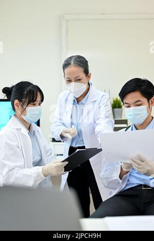 A professional and successful Asian senior female medical doctor specialist supervisor training and teaching two young Asian junior specialist in the Stock Photo