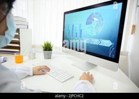 A male scientist working at his office desk looking at his desktop computer with science analysis workflow chart on the screen. close-up image Stock Photo