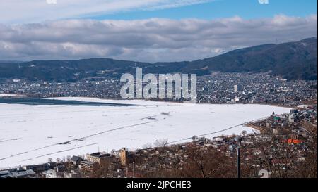 An overview of frozen Lake Suwa and Suwa City in winter in Nagano, Japan. Stock Photo