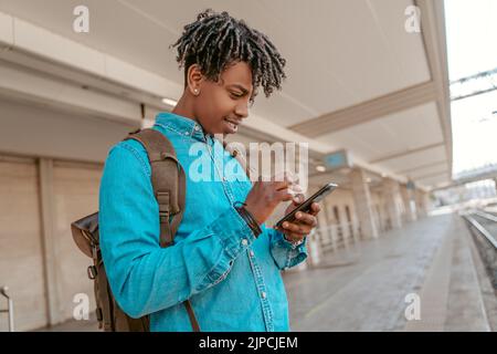 Guy looking at smartphone waiting for arrival of train Stock Photo