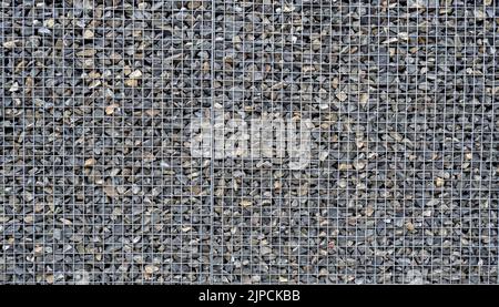 Gabion with heaps of small stones in a grid as the city or garden decoration, textured background Stock Photo