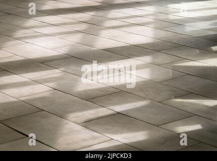 Abstract shadows, silhouettes, lines on the tiled floor through a window during sunny day Stock Photo