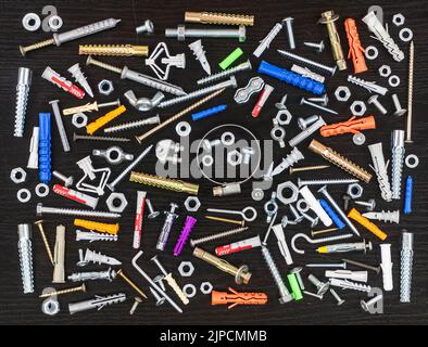 Different types of fasteners on a dark wood background. View from above. Stock Photo
