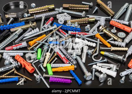 Different types of fasteners on a dark wood background. Front view. Stock Photo