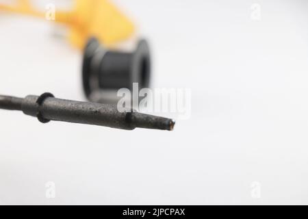 Soldering iron that is used a lot of times closeup view with empty roll of soldering wire on the background Stock Photo