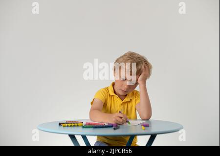 Boy with a pencil sitting at a table, school education Stock Photo