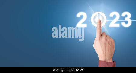 Finger pressing start 2023 button on virtual interface. Businessman pressing 2023 start up business. Happy New Year button technology virtual innovati Stock Photo