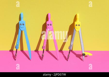 Creative back to school concept. Compass divider with shadow of sun on pink and yellow color background. Copy space. Stock Photo