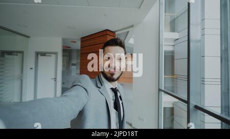 POV of young businessman in suit taking a selfie photo and have fun in modern office indoors Stock Photo