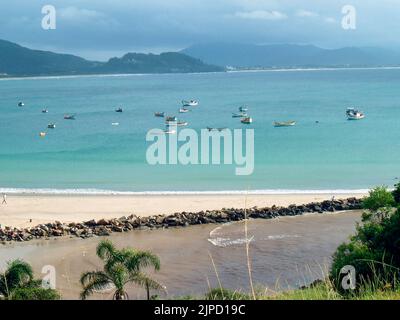 Small boats in the blue sea with calm waves under a cloudy sky in Brazil Stock Photo