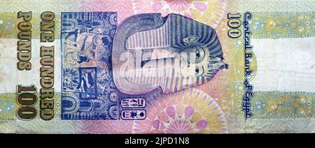 Large fragment of reverse side of an old 100 LE EGP one hundred Egyptian cash money banknote Tutankhamen's mask above frieze at centre of vertical for Stock Photo